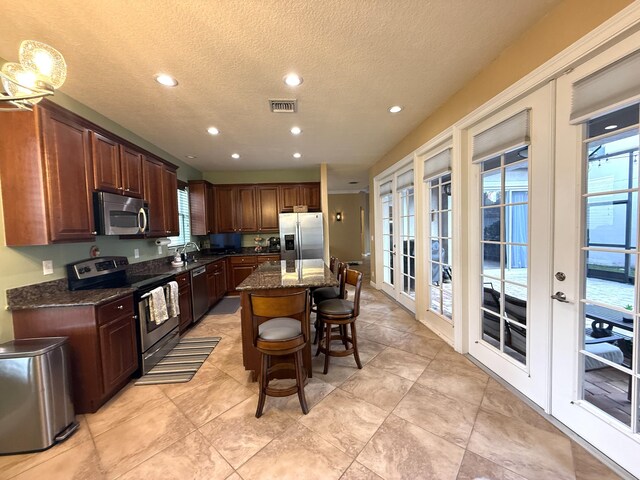 kitchen featuring visible vents, a kitchen bar, a center island, french doors, and appliances with stainless steel finishes