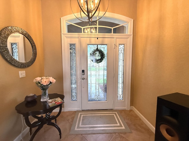 tiled entrance foyer with a notable chandelier and baseboards