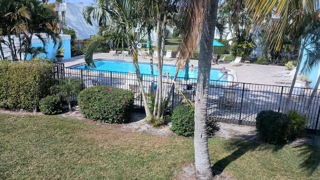 community pool with a patio, fence, and a lawn