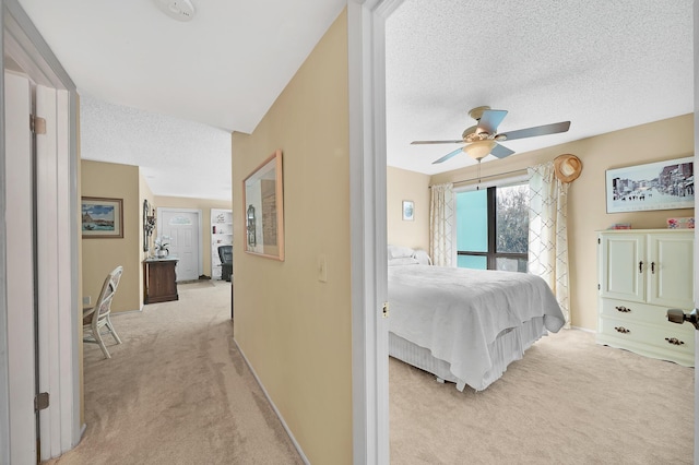 bedroom featuring baseboards, light carpet, a textured ceiling, and a ceiling fan