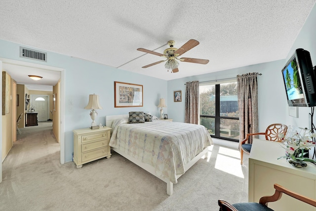 bedroom with light carpet, visible vents, a textured ceiling, and ceiling fan