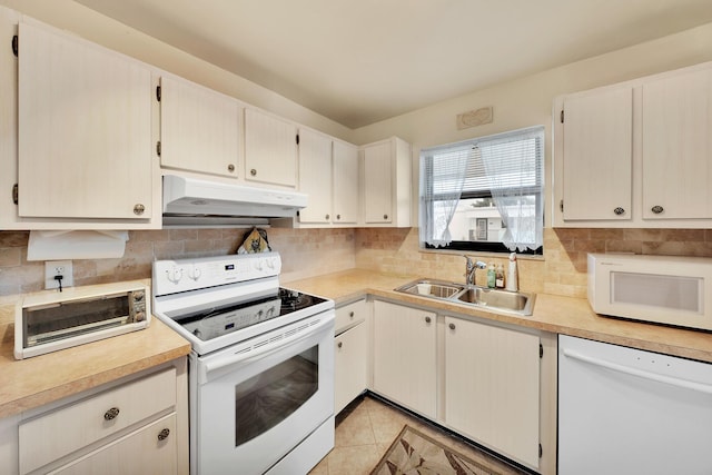 kitchen featuring white appliances, a sink, decorative backsplash, light countertops, and under cabinet range hood