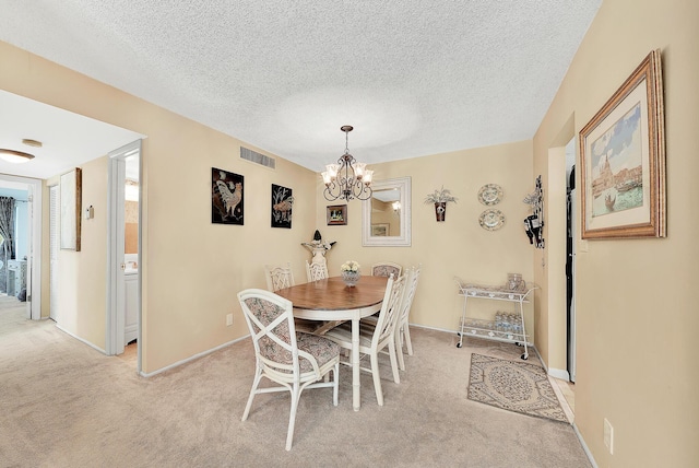 dining area with visible vents, light colored carpet, a notable chandelier, and a textured ceiling