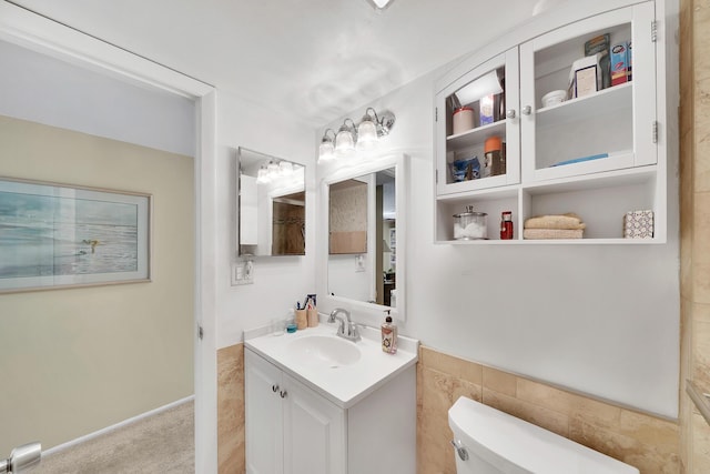 bathroom featuring toilet, tile walls, and vanity