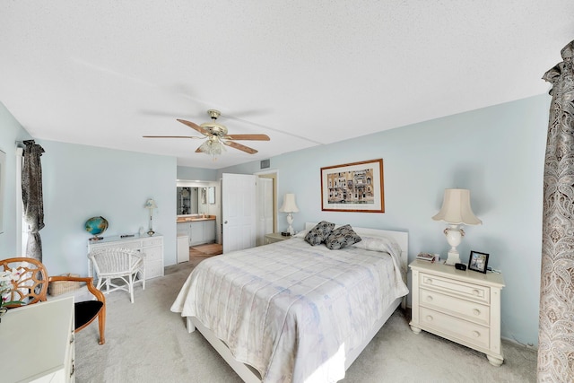 bedroom featuring visible vents, light colored carpet, connected bathroom, and a ceiling fan