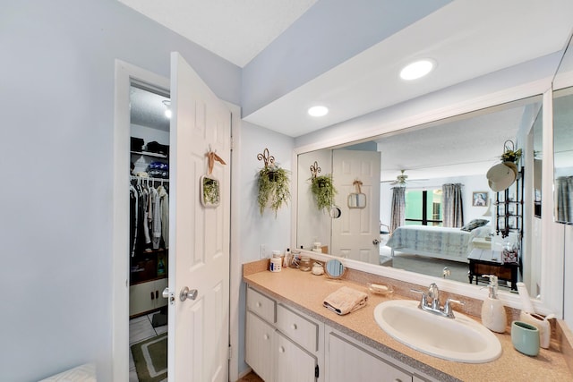 ensuite bathroom with a walk in closet, ensuite bathroom, a ceiling fan, recessed lighting, and vanity