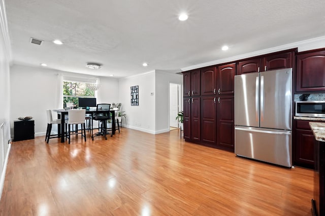 kitchen featuring stainless steel appliances, a textured ceiling, and light wood-type flooring