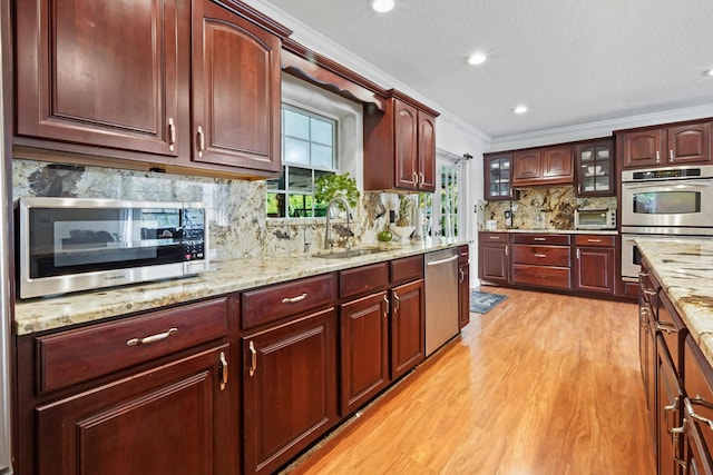 kitchen with sink, crown molding, light hardwood / wood-style flooring, stainless steel appliances, and tasteful backsplash