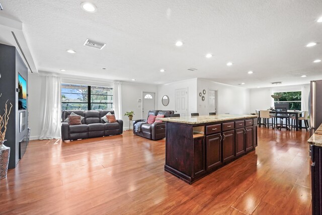 kitchen featuring hardwood / wood-style flooring, a healthy amount of sunlight, a center island, and dark brown cabinets