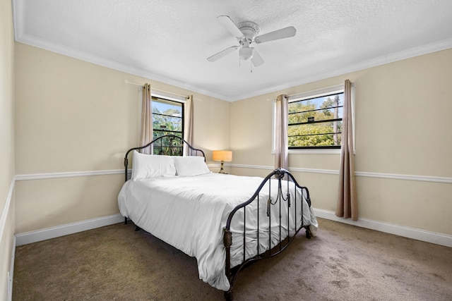 bedroom with ceiling fan, ornamental molding, a textured ceiling, and dark colored carpet