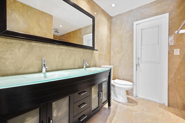 bathroom with vanity, toilet, and tile walls