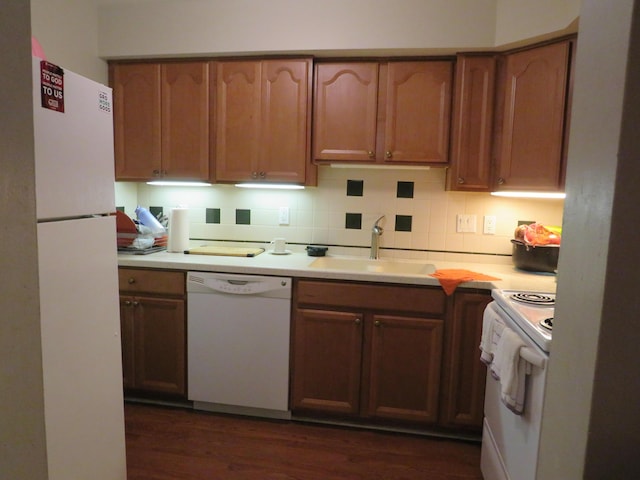 kitchen with dark hardwood / wood-style floors, sink, white appliances, and decorative backsplash