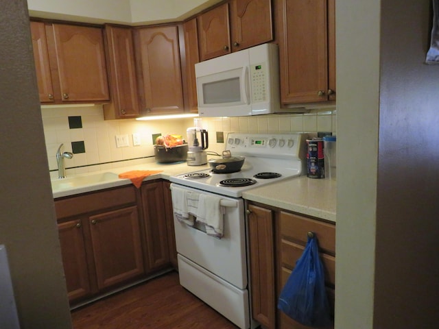 kitchen with sink, dark wood-type flooring, white appliances, and decorative backsplash