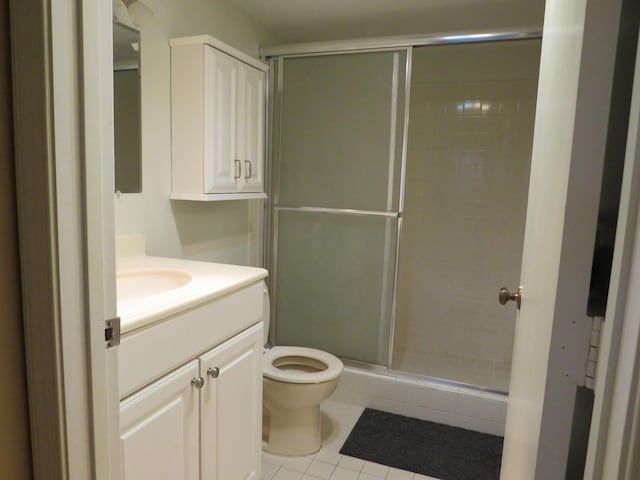 bathroom with tile patterned floors, vanity, toilet, and a shower with door