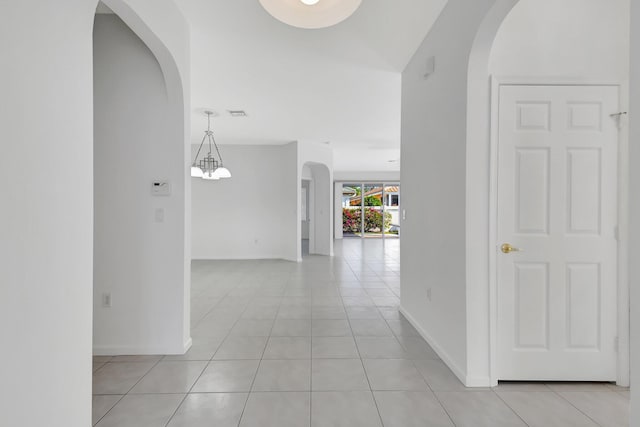 corridor with light tile patterned flooring and a chandelier