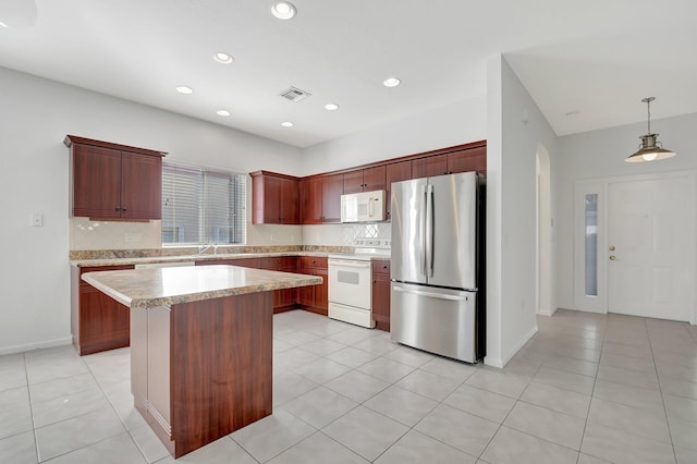 kitchen with hanging light fixtures, a kitchen island, backsplash, and white appliances