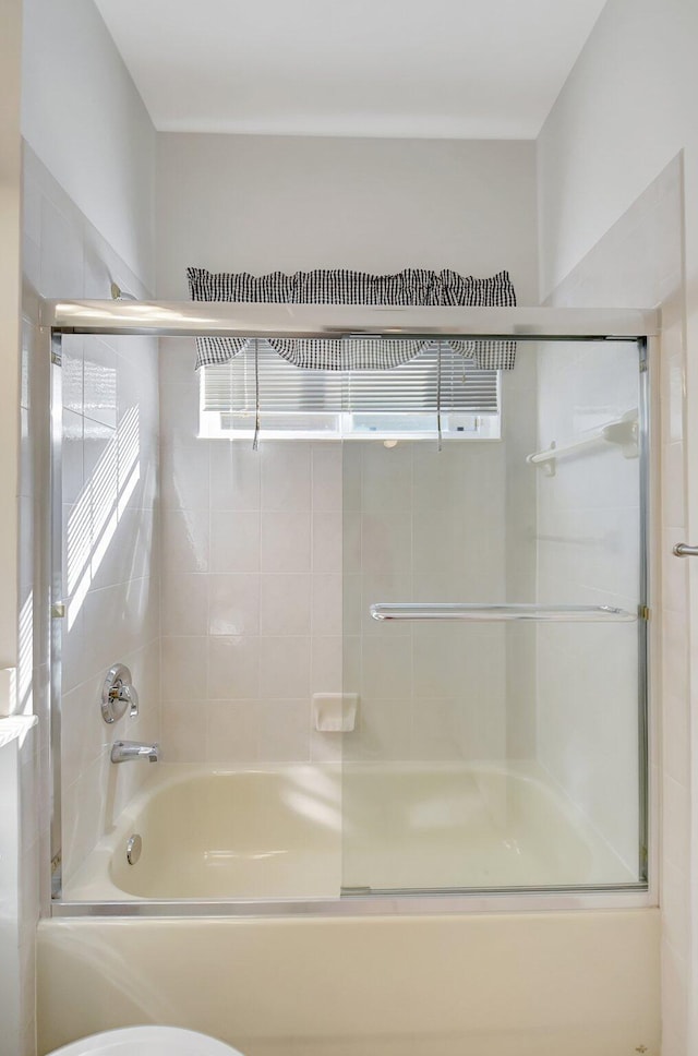 bathroom with enclosed tub / shower combo and toilet