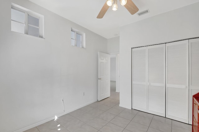 unfurnished bedroom with ceiling fan, a closet, and light tile patterned floors