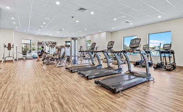 exercise room with light hardwood / wood-style flooring and a paneled ceiling