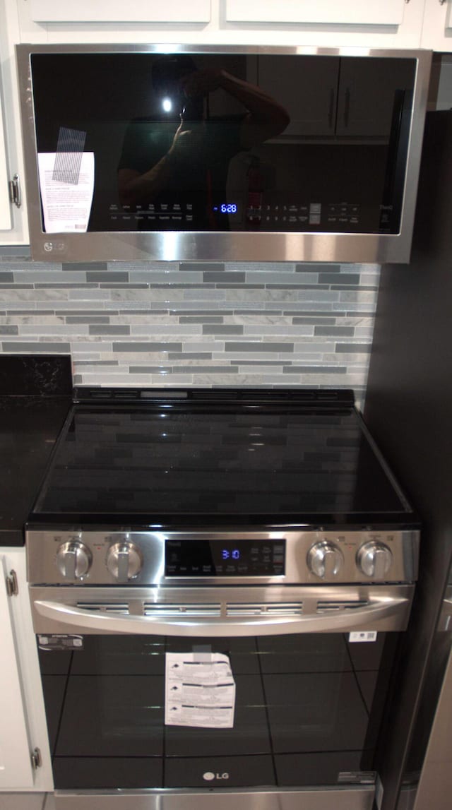 kitchen with white cabinetry, stainless steel appliances, and backsplash