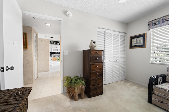 bedroom with a closet, light carpet, and a textured ceiling