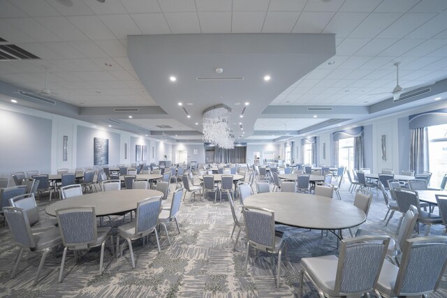 dining space with a raised ceiling, carpet, and a drop ceiling