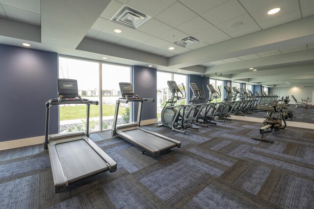 workout area with dark colored carpet and a drop ceiling