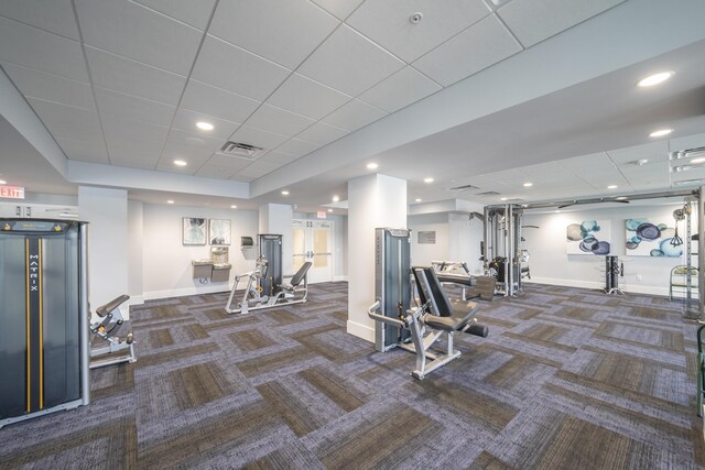 workout area with a tray ceiling, dark carpet, a paneled ceiling, and floor to ceiling windows