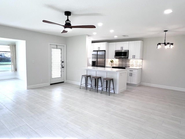 kitchen with pendant lighting, a breakfast bar, appliances with stainless steel finishes, white cabinets, and a kitchen island