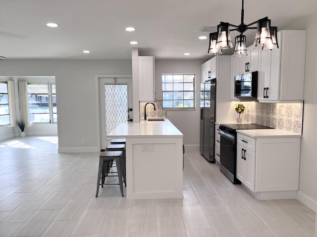 kitchen with decorative light fixtures, white cabinetry, an island with sink, sink, and stainless steel appliances