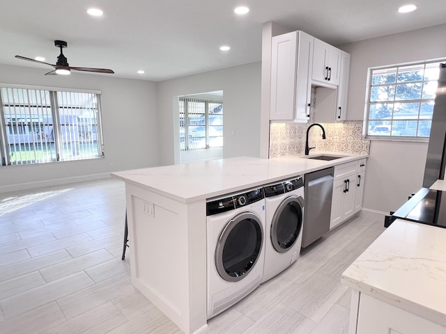 kitchen with sink, ceiling fan, independent washer and dryer, tasteful backsplash, and stainless steel dishwasher