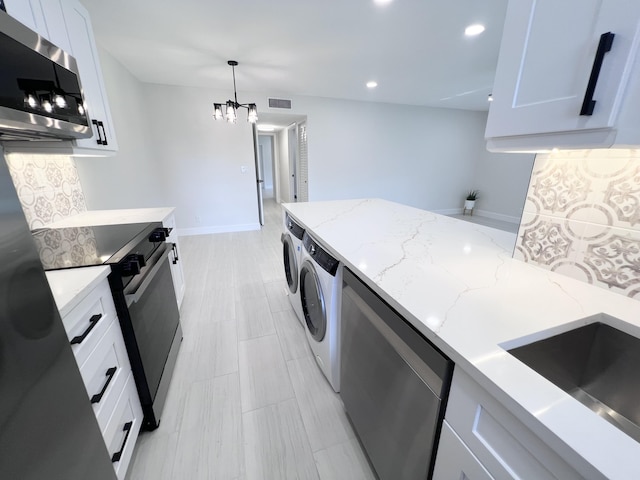 kitchen with white cabinetry, light stone counters, decorative light fixtures, washer and dryer, and appliances with stainless steel finishes