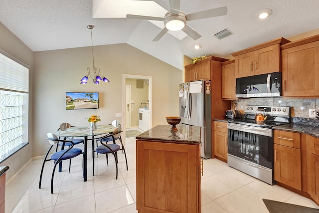 kitchen featuring light tile patterned flooring, appliances with stainless steel finishes, decorative light fixtures, lofted ceiling, and a center island