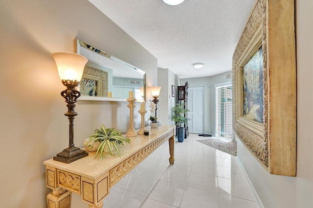 hallway with a textured ceiling and light tile patterned floors