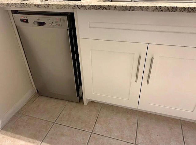 interior details with light stone counters, white cabinetry, and dishwasher