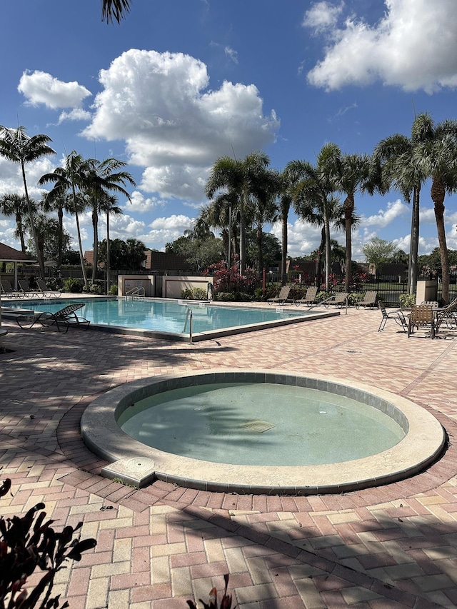 view of pool with a hot tub and a patio area