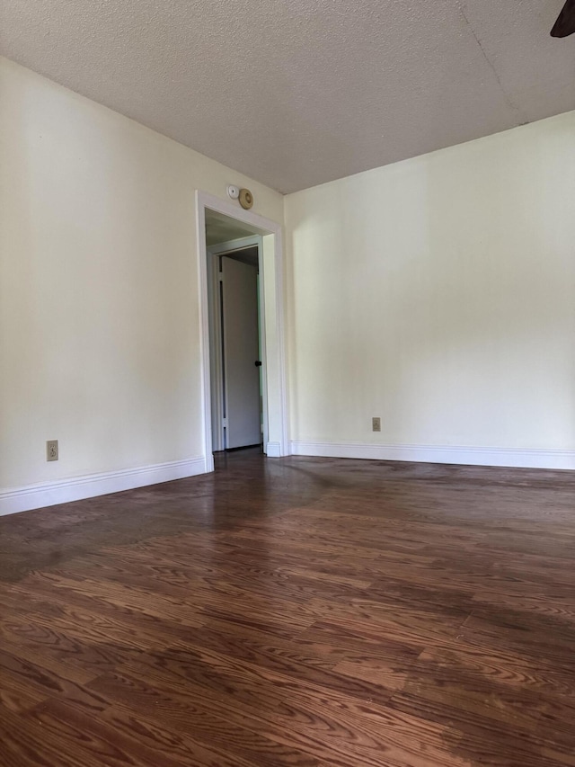 unfurnished room with dark wood-type flooring and a textured ceiling