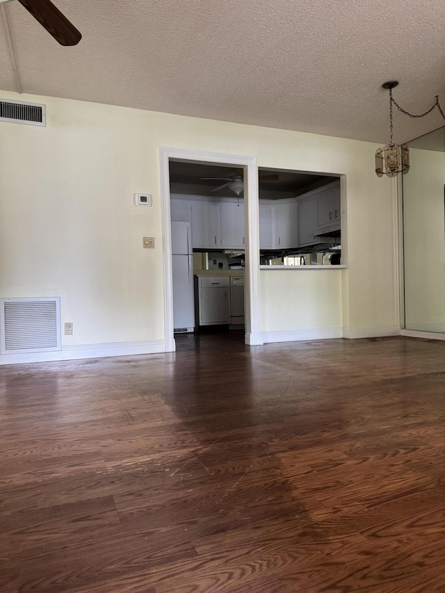 unfurnished living room featuring a textured ceiling, dark wood-type flooring, and ceiling fan