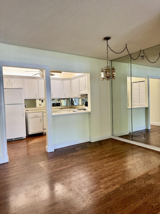 kitchen featuring decorative light fixtures, dark hardwood / wood-style floors, white fridge, ceiling fan with notable chandelier, and white cabinets