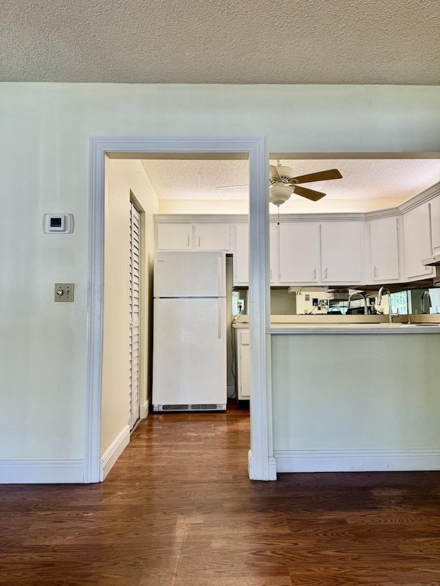 kitchen with dark wood-type flooring, ceiling fan, white refrigerator, a textured ceiling, and white cabinets