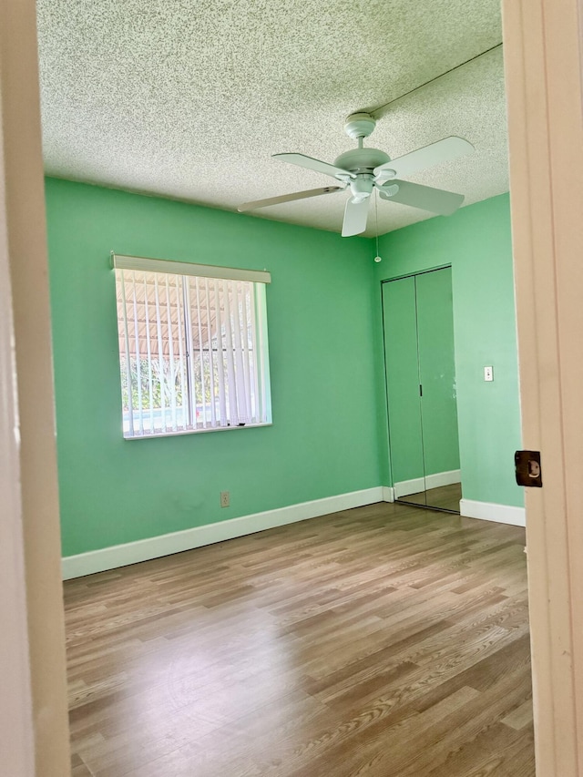 unfurnished bedroom with ceiling fan, a closet, a textured ceiling, and light wood-type flooring