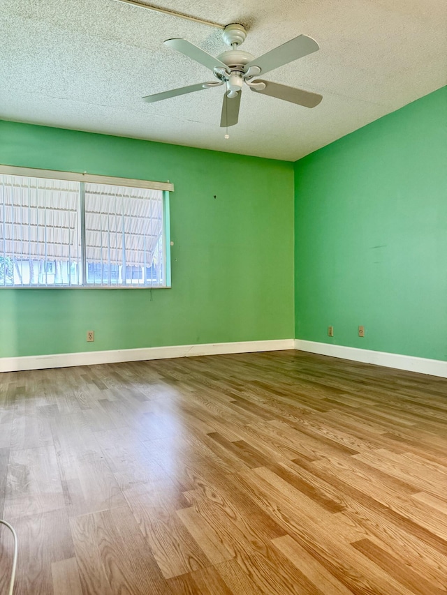 empty room with ceiling fan, a textured ceiling, and light wood-type flooring