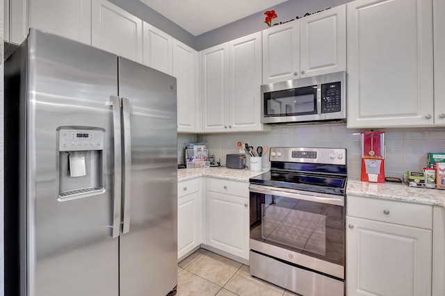 kitchen with decorative backsplash, light tile patterned flooring, white cabinets, and appliances with stainless steel finishes