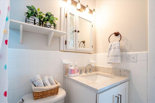 bathroom featuring vanity, toilet, and tile walls