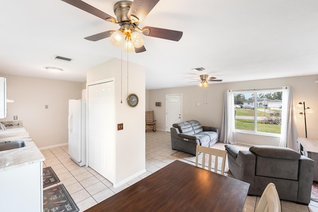 dining space featuring light tile patterned flooring, ceiling fan, and sink