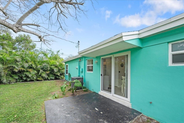 entrance to property with a yard, a patio, and central air condition unit