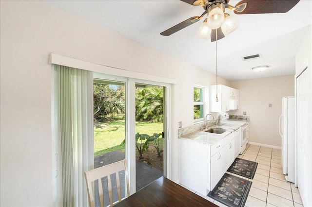 kitchen with white cabinetry, sink, light tile patterned floors, ceiling fan, and white appliances