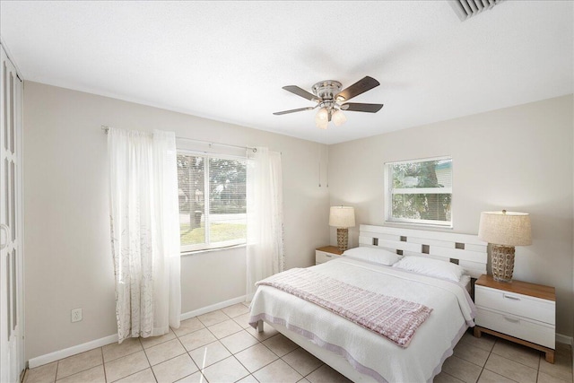 tiled bedroom featuring multiple windows and ceiling fan