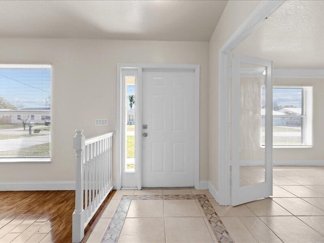 tiled entryway featuring plenty of natural light, baseboards, and a textured ceiling