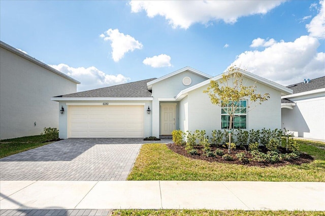 ranch-style house with an attached garage, roof with shingles, decorative driveway, stucco siding, and a front yard